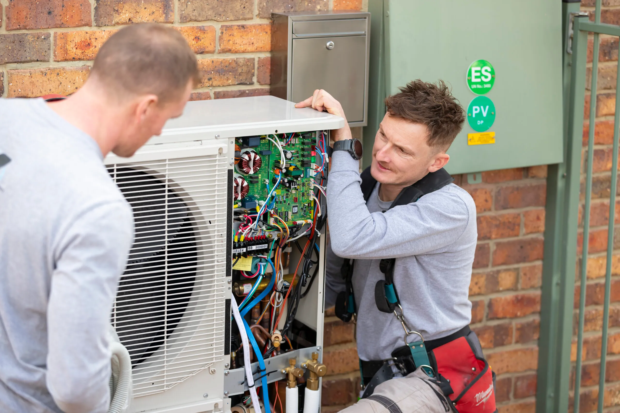 Two Fused Electrical Co electricians installing a heat pump