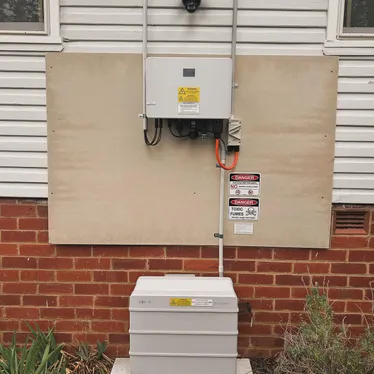 Home battery installed on the outside wall of a weatherboard house