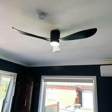 Black ceiling fan with a light fitted in the ceiling of a living room