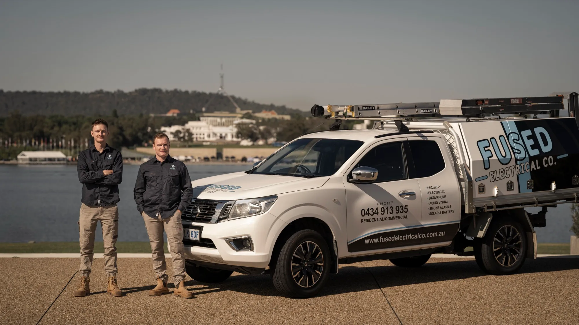 Nicolas and Andre Menager of Fused Electrical Co with their work ute beside Lake Burley Griffin