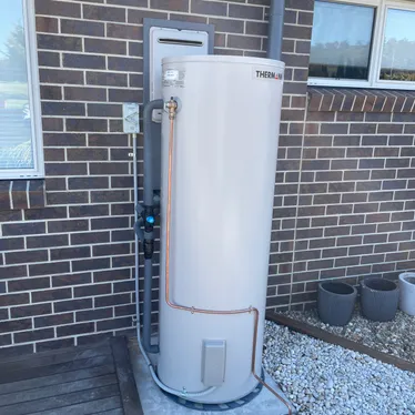 Heat pump hot water unit installed beside a brick home