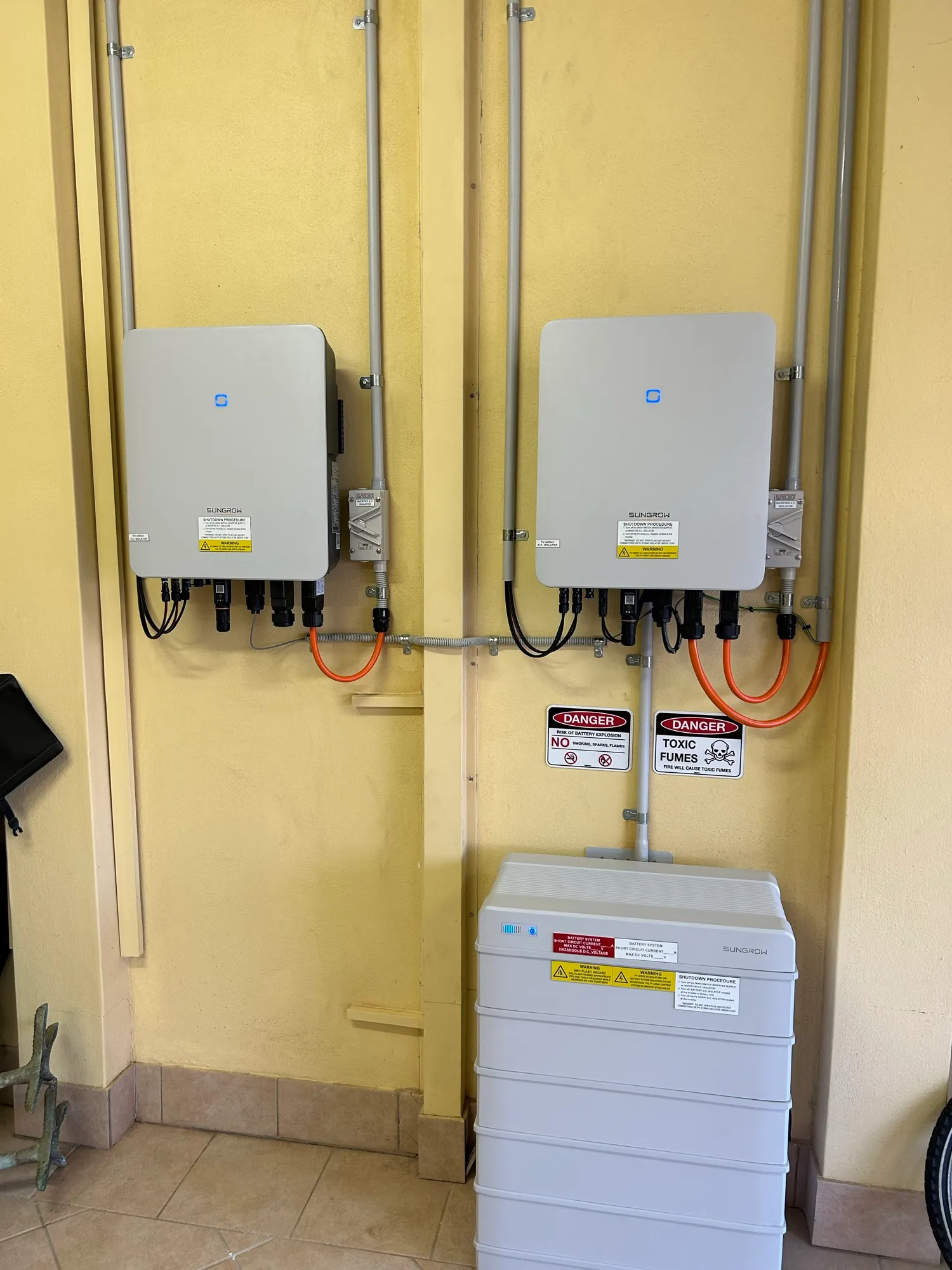 Two solar inverters and a home battery installed on a garage wall