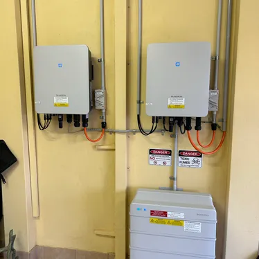 Two solar inverters and a home battery installed on a garage wall