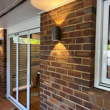 Up and down wall lights on a brick feature wall at an entry
